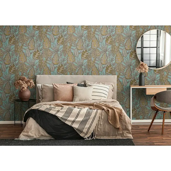 A.S. Création Famous Garden Vliestapete Blatt - Hellblau-Gelb-Braun, Floral, 10,05 x 0,53 m - Schlafzimmer mit einem bequemen Bett, dekoriert mit Kissen und einer Decke, vor einer Wand mit floralem Muster und einem runden Spiegel.