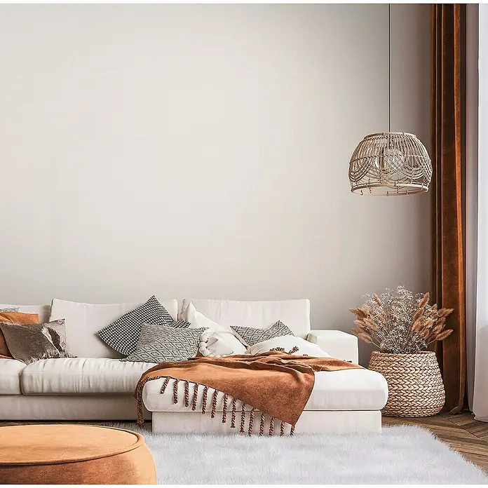 A.S. Création Famous Garden Vliestapete - Creme-Weiß-Beige, Uni, 10,05 x 0,53 m - Wohnzimmer mit weißem Sofa, Zierkissen, brauner Decke und Hängelampe für ein gemütliches Ambiente.