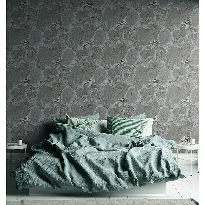 A.S. Création Famous Garden Vliestapete Dschungel - Grau-Anthrazit, Floral, 10,05 x 0,53 m - Einladendes Schlafzimmer mit mintgrüner Bettwäsche auf einem gemütlichen Bett vor einer eleganten Blättertapete.