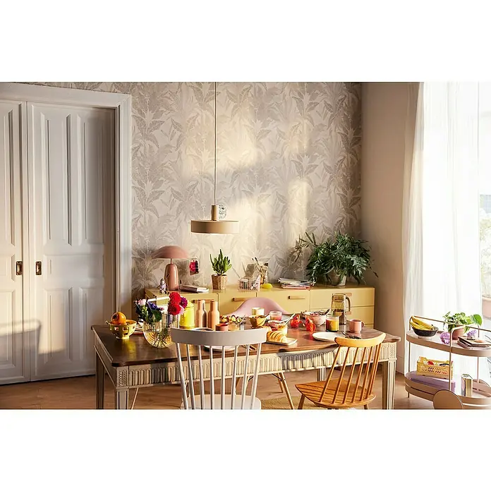 A.S. Création Stories of Life Vliestapete Dschungel - Beige-Gold, Floral, 10,05 x 0,53 m - Esszimmerszene mit Holztisch, Geschirr, Stühlen und einem beigen Sideboard unter einer Pendelleuchte für ein gemütliches Ambiente.