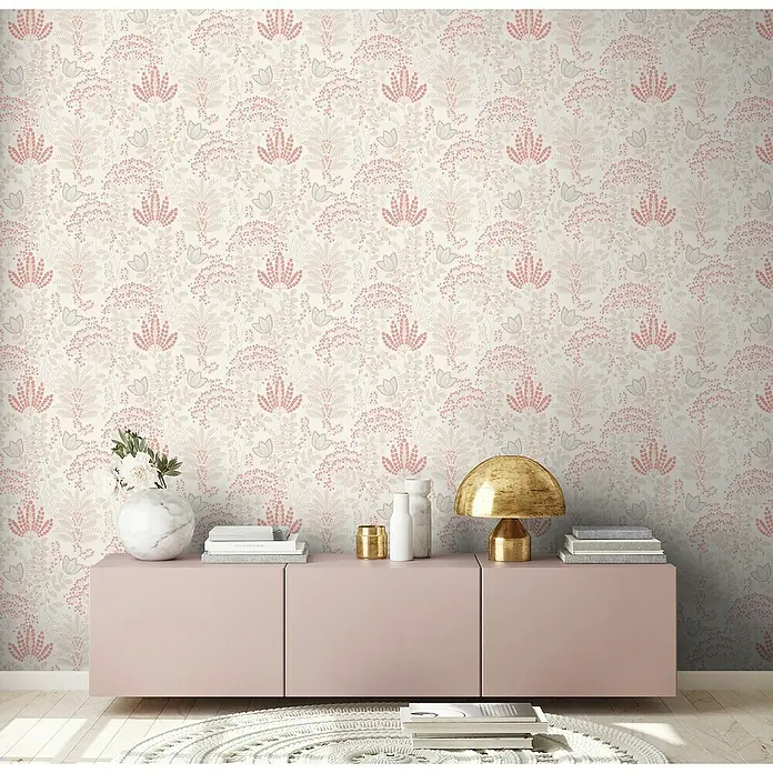 A.S. Création Famous Garden Vliestapete - Weiß-Taupe-Rosa, Floral, 10,05 x 0,53 m - Rosa Sideboard mit diversen Dekoartikeln und einer goldenen Lampe vor einer floralen Tapete als dekorativer Akzent im Raum.