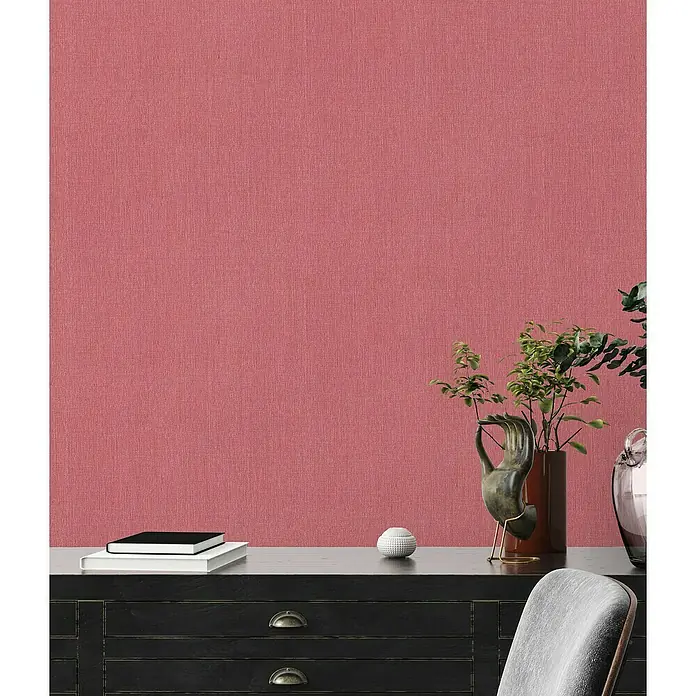 A.S. Création Stories of Life Vliestapete - Rot, Uni, 10,05 x 0,53 m - Nahaufnahme einer dezent gemusterten Wand mit einem eleganten Sideboard und dekorativen Elementen, die eine stilvolle Wohnatmosphäre schaffen.