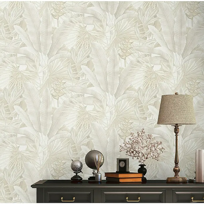 A.S. Création Stories of Life Vliestapete - Beige-Creme-Grau, Floral, 10,05 x 0,53 m - Elegante Tapete mit tropischem Blättermuster und Dekorationen auf einem dunklen Sideboard, inklusive Lampe, Büchern und einer Uhr.