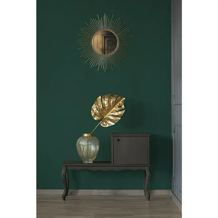 A.S. Création Stories of Life Vliestapete - Grün-Dunkelgrün, Uni, 10,05 x 0,53 m - Elegante Einrichtung mit einem Spiegel in Sonnenform und einer goldenen Monstera-Blattdekoration in einer stilvollen Vase auf einem Konsolentisch.