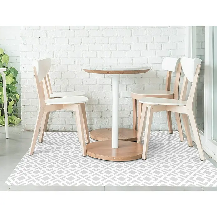 Alfombra de vinilo Living geométrica - Gris, 180 x 120 cm - Un acogedor espacio al aire libre con una mesa redonda y tres sillas de madera clara sobre un suelo de vinilo estampado.
