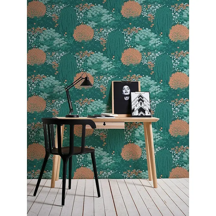 A.S. Création Famous Garden Vliestapete - Petrol-Orange-Grün, Floral, 10,05 x 0,53 m - Schreibtisch mit natürlichem Holz, schwarzem Stuhl und Lampe vor einer botanischen Tapete mit Bäumen und Blumen.