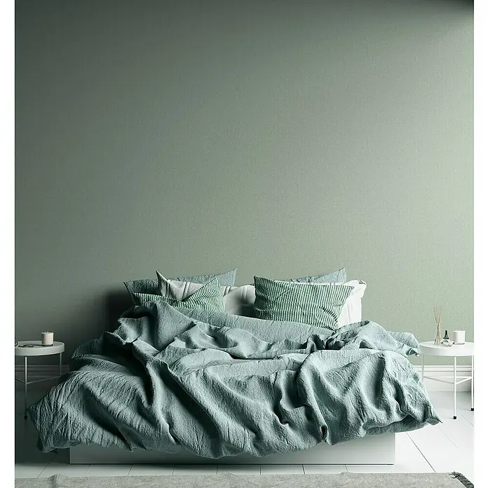 A.S. Création Famous Garden Vliestapete - Grün, Uni, 10,05 x 0,53 m - Stilvolles Schlafzimmer mit einem großen Bett, bezogen mit einer hellgrünen Decke und Kissen, die eine beruhigende Atmosphäre schaffen.