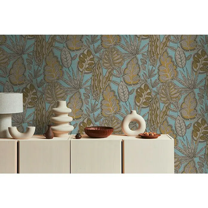 A.S. Création Famous Garden Vliestapete Blatt - Hellblau-Gelb-Braun, Floral, 10,05 x 0,53 m - Einrichtungsfoto mit dekorativen Keramikvasen und Schalen auf einer weißen Kommode vor einer blauen Blättertapete.