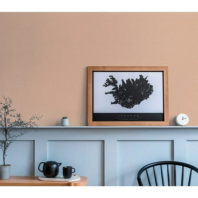 A.S. Création Famous Garden Vliestapete - Rosa, Uni, 10,05 x 0,53 m - Ein gerahmtes Island-Poster ist auf einem Regal zu sehen, zusammen mit Pflanzen und einer Teekanne, die eine gemütliche Atmosphäre erzeugen.