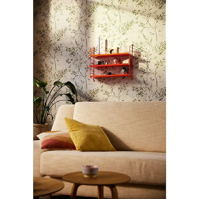 A.S. Création Stories of Life Vliestapete Zweig - Beige-Grün-Gold, Floral, 10,05 x 0,53 m - Nahaufnahme einer trendigen orangefarbenen Wandregal, das mit dekorativen Objekten in einem stilvollen Raum versehen ist.