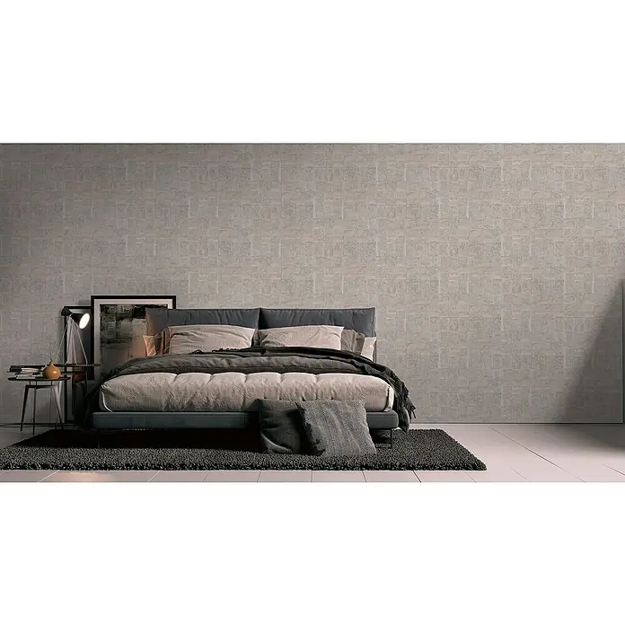 A.S. Création Stories of Life Vliestapete - Gold-Grau Metallic, Grafisch, 10,05 x 0,53 m - Elegantes Schlafzimmer mit einem grauen Bett und einer gemusterten Wand. Die Einrichtung ist modern und stilvoll.