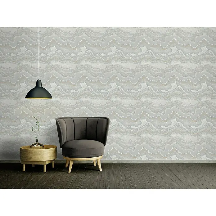 A.S. Création Stories of Life Vliestapete Marmoroptik Metallic-Effekt - Grau-Silber-Gold, Steinoptik, 10,05 x 0,53 m - Interieuransicht mit einem stilvollen Sessel und einer eleganten Pendelleuchte vor einer gemusterten Wand.