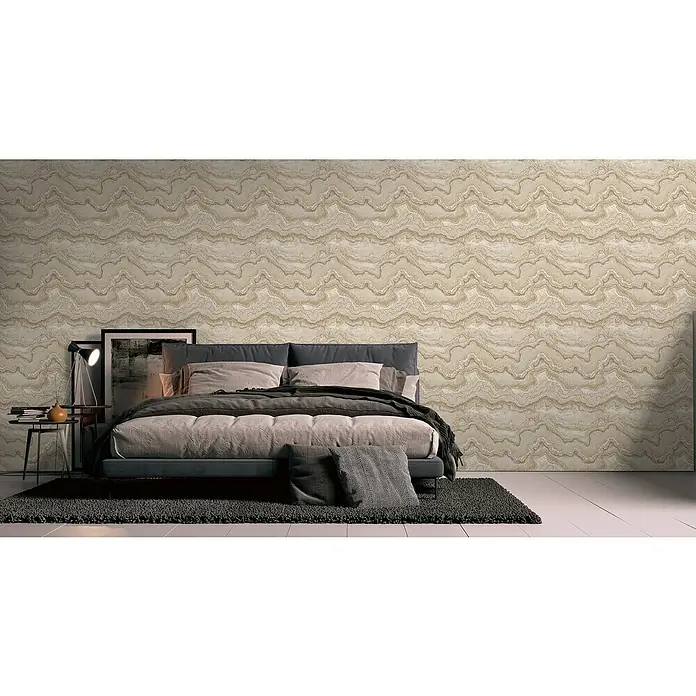 A.S. Création Stories of Life Vliestapete Marmoroptik Metallic-Effekt - Sandcreme, Steinoptik, 10,05 x 0,53 m - Elegantes Schlafzimmer mit einem komfortablen Bett in Grau und Beige, ergänzt durch eine gemusterte Tapete und einen dunklen Teppich.