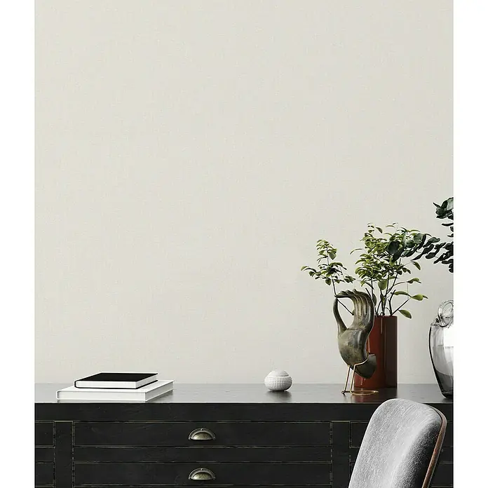 A.S. Création Famous Garden Vliestapete - Creme-Weiß, Uni, 10,05 x 0,53 m - Elegantes Sideboard in Schwarz mit dekorativen Elementen wie Pflanzen, Büchern und einer Skulptur, die eine harmonische Atmosphäre schaffen.