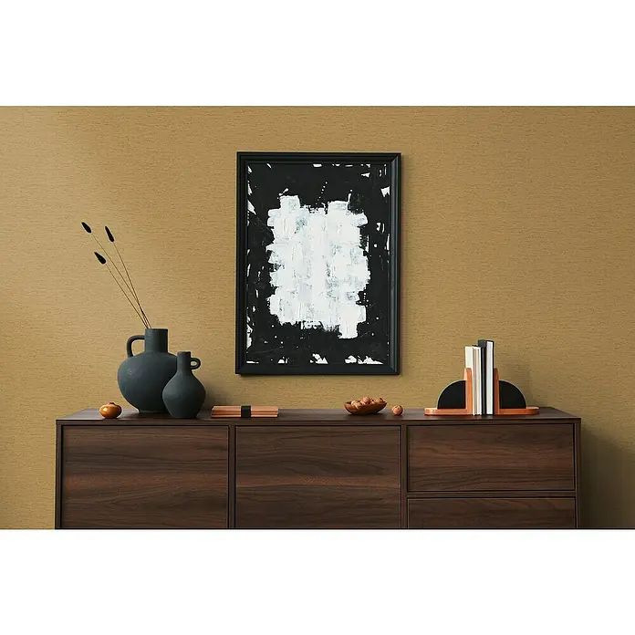 A.S. Création Famous Garden Vliestapete - Goldbraun-Gelb, Uni, 10,05 x 0,53 m - Das moderne Sideboard aus dunklem Holz mit abstrakter Kunst und dekorativen Objekten bietet viel Stauraum und ist ein stilvoller Blickfang.