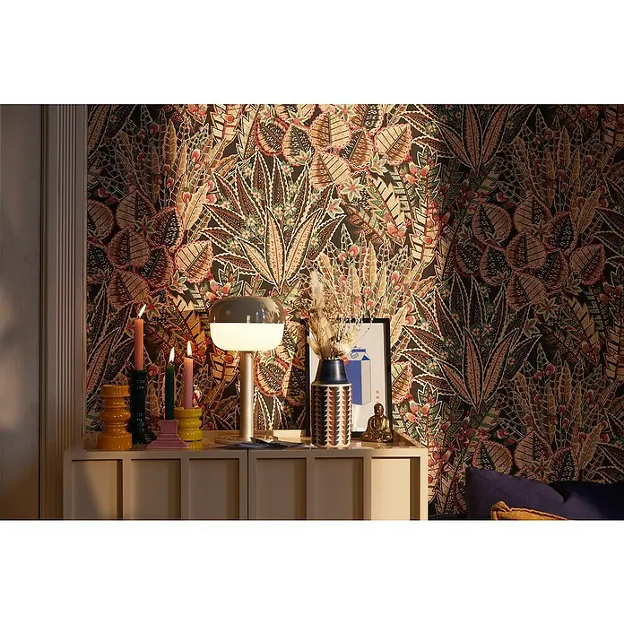 A.S. Création Stories of Life Vliestapete Blumen - Braun-Rot-Schwarz, Floral, 10,05 x 0,53 m - Stimmungsvolle Aufnahme eines Sideboards mit Kerzenhaltern und einer Lampe vor einer floral gemusterten Tapete.
