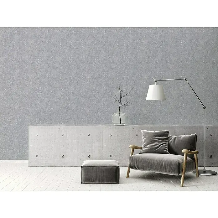 A.S. Création Stories of Life Vliestapete Used-Look - Betongrau-Silber, Betonoptik, 10,05 x 0,53 m - Graues Interieur mit stilvollem Sessel, Hocker, Lampe und Betonkonsole vor einer grauen Wand für ein modernes Ambiente.