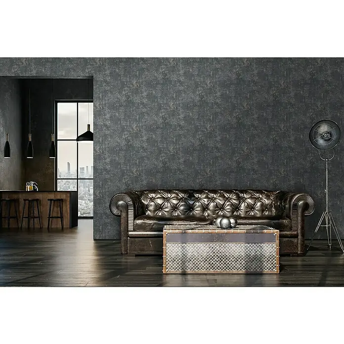 A.S. Création Stories of Life Vliestapete Patina - Schwarz-Roségold, Betonoptik, 10,05 x 0,53 m - Elegantes Interieur mit braunem Ledersofa und einem industriellen Couchtisch, akzentuiert durch eine Stehlampe.