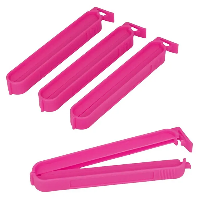 Metaltex Clips - 4 Stk., L x B x H: 11 x 1,2 x 1,5 cm - Nahaufnahme von vier pinkfarbenen Chipstütenverschlüssen, drei davon geschlossen und einer geöffnet, auf schwarzem Hintergrund.