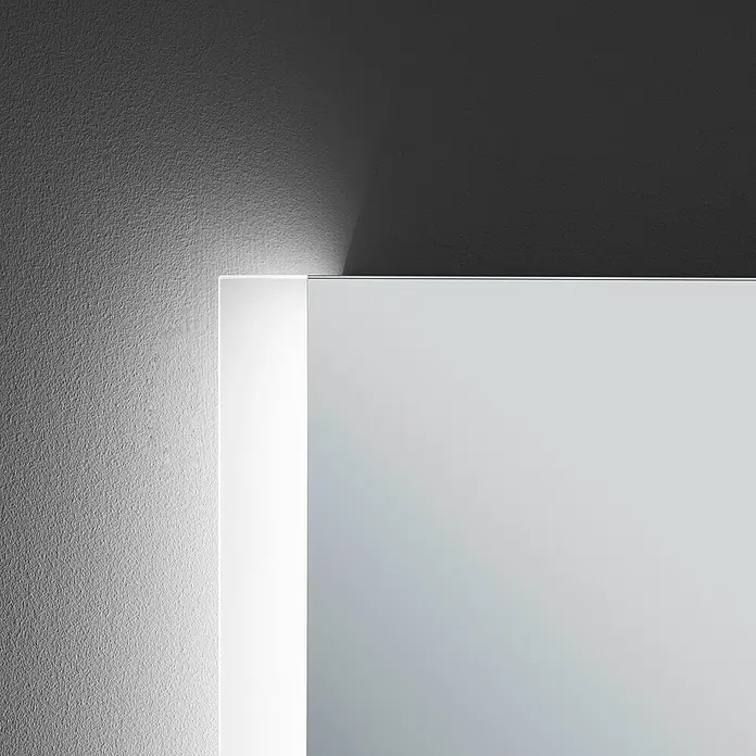 Camargue Lichtspiegel Aran - 100 x 70 cm, Leuchtmittel - Nahaufnahme eines modernen Spiegels mit integrierter Beleuchtung an einer strukturierten Wand. Das Licht betont die minimalistische Ästhetik.