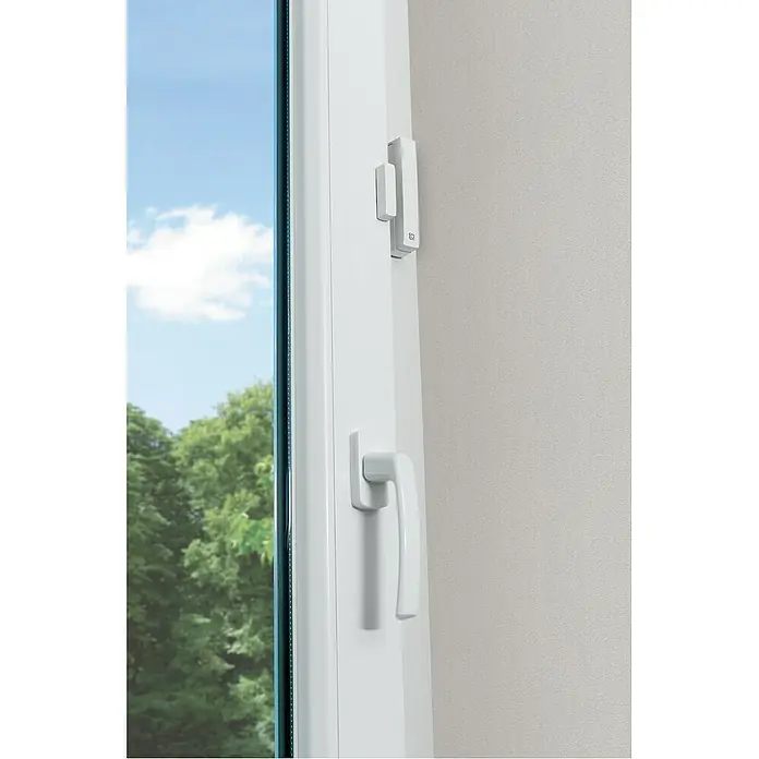 Homematic IP Starter-Set Heizen Easy Connect - 1 x Heizkörperthermostat, 1 x Fenster- und Türkontakt, 1 x Adapter Danfoss RA, 1 x Stützring, 1 x Montagematerial, 4 x Batterien, 1 x Bedienungsanleitung - Nahaufnahme eines weißen Fensters mit Griff und Fensteranschluss, der in einem modernen Haus Sicherheit und Komfort bietet.