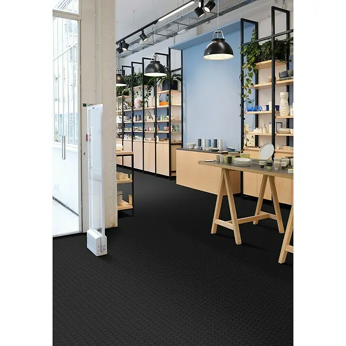 Beauflor PVC-Boden Meterware Novo - 200 cm, Solid Disc, Grau/Schwarz - Einladendes Ladendesign mit Regalen und minimalistischer Einrichtung, präsentiert auf stilvollem, dunklem Bodenbelag mit subtilem Muster.