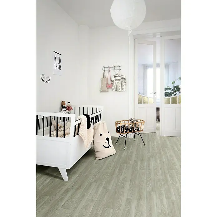 Beauflor PVC-Boden Meterware Feelings - 400 cm, Chapman Oak, Grau - Ein Kinderzimmer mit einem weißen Gitterbett, einer Wiege und einem Bärenkissen auf einem hellgrauen Holzboden.