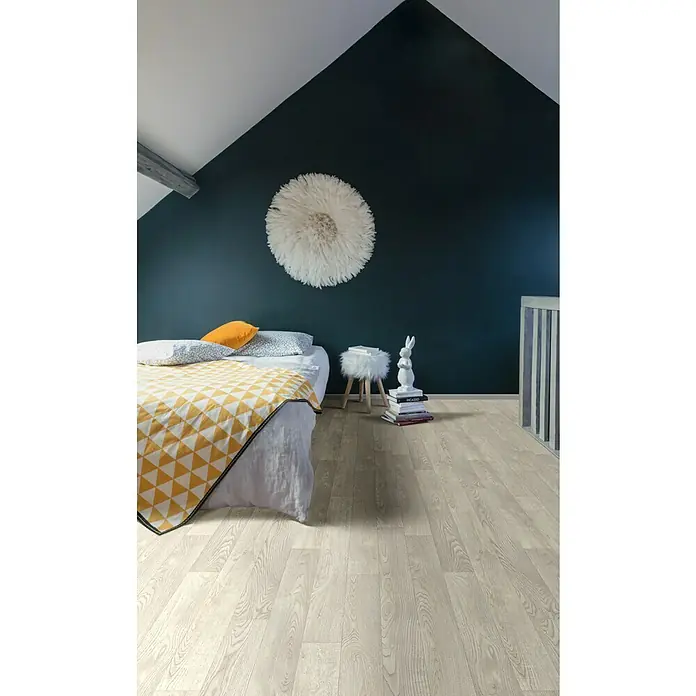 Beauflor PVC-Boden Meterware Sherwood - 400 cm, White Oak 167S, Beige - Ein Schlafzimmer mit hellem Holzfußboden, einem Bett mit gelber Decke und einer dunklen Wand mit einem dekorativen weißen Ornament.