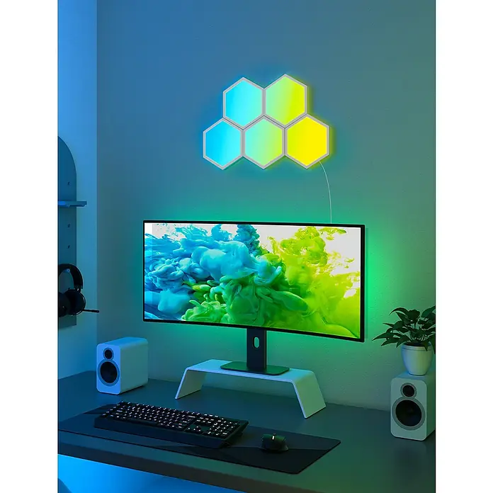 Govee Starterkit Glide Hexa Light Panels B6061 - Weiß - Moderne Spielestation mit einem grossen Monitor und hexagonförmigen LED-Wandleuchten, die eine einzigartige Atmosphäre schaffen.