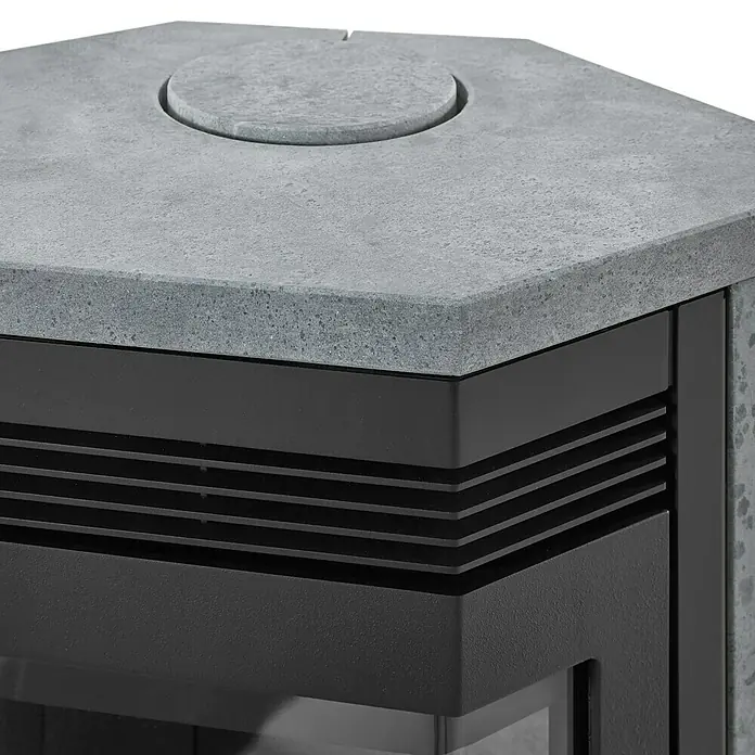 Justus Kaminofen Usedom 5 II - 5,5 kW, Raumheizvermögen: 88 m³, Material Verkleidung: Speckstein, Schwarz/Speckstein - Detailaufnahme eines modernen Kaminofens mit grauer Steinplatte und schwarzen Akzenten. Das Design ist schlicht und zeitgemäß.