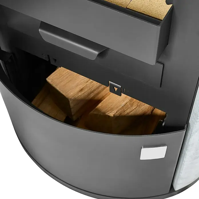 Justus Kaminofen Austin 7 - 7 kW, Raumheizvermögen: 144 m³, Material Verkleidung: Speckstein, Schwarz/Speckstein - Nahaufnahme eines Holzofen mit Holzlagerung. Praktische Aufbewahrung für Brennholz direkt unter dem Ofen für einfache Bedienung.