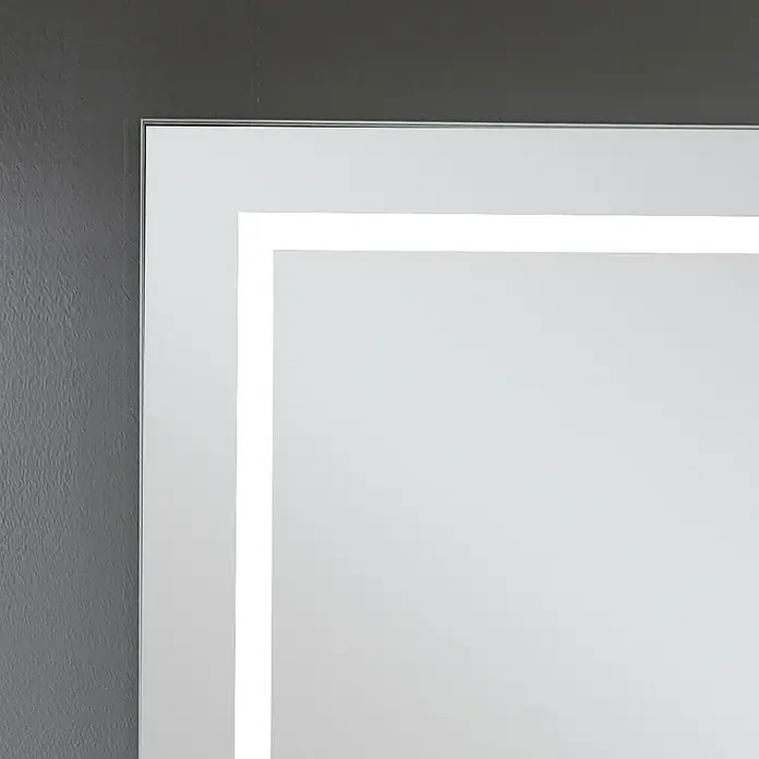 Camargue Lichtspiegel Linnea60 x 70 cm, Leuchtmittel - Nahaufnahme eines beleuchteten Spiegels mit silbernem Rahmen an einer grauen Wand, der ein modernes und elegantes Design zeigt.