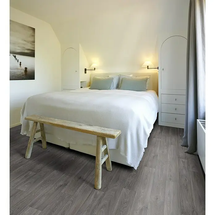 Beauflor PVC-Boden Meterware Feelings - 300 cm, Havanna Oak, Taupe - Einladendes Schlafzimmer mit einem Holzbett, einer rustikalen Bank und einem stilvollen grauen Holzboden, der Wärme und Eleganz vereint.