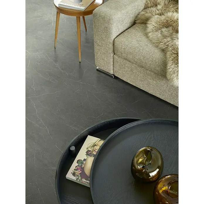 Beauflor PVC-Boden Meterware Cupid - Steinoptik, Breite: 400 cm, Schwarz - Nahaufnahme eines modernen Wohnzimmers mit Marmorboden und elegantem Couchtisch mit Dekorationsgegenständen.