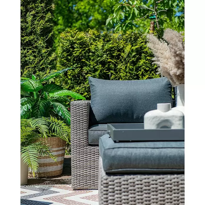 Garden Impressions Loungemöbel-Set Orangebird - 4 -tlg., Aluminium, Schwarz/Grau - Geflochtener Outdoor-Sessel und Hocker mit dunkelgrauen Polstern auf einer Terrasse, mit Deko-Tablett.