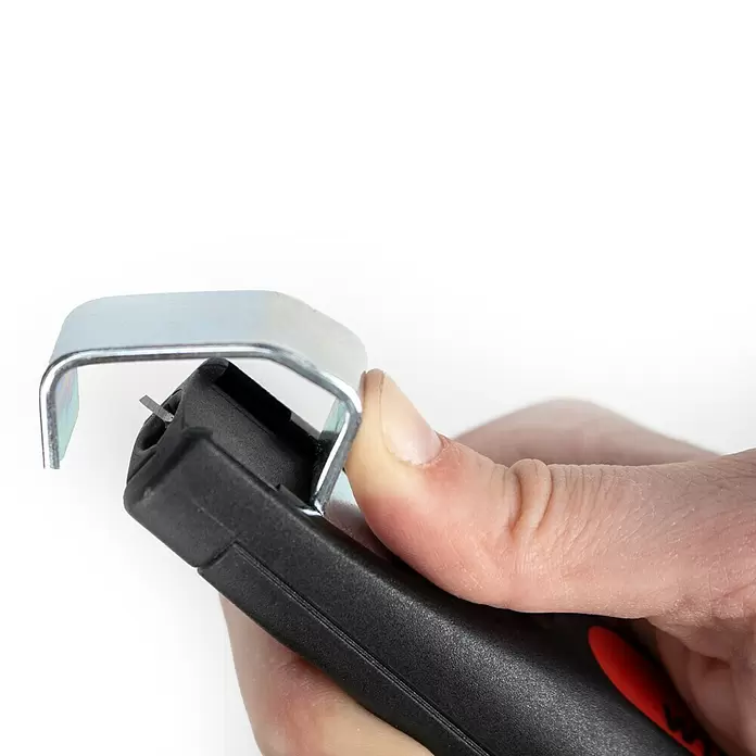 Wiha Kabelabmantelungsmesser mit Schleppklinge - Passend für: Rundkabel 4 - 28 mm - Hand hält schwarzes und rotes Werkzeug, das ein Metallteil greift. Eine scharfe Klinge zum Schneiden oder Abisolieren ist sichtbar.