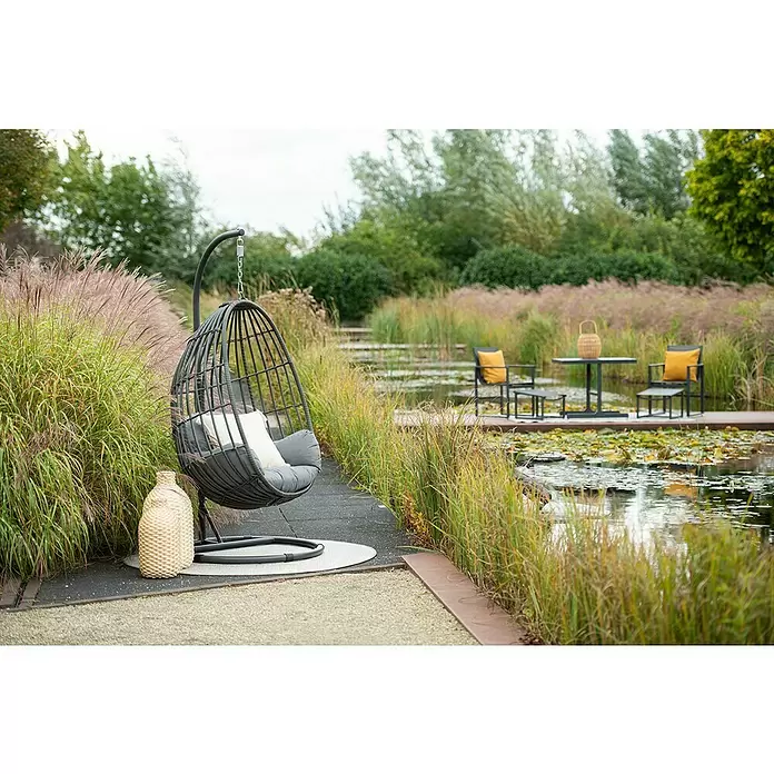 Garden Impressions Hängesessel Panama - L x B x H: 195 x 195 x 90 cm, Metall, Dunkelgrau - Dunkelgrauer Rattan-Eier-Schaukelstuhl mit hellen Kissen auf einer Terrasse, mit Blick auf einen Teich mit Seerosen.