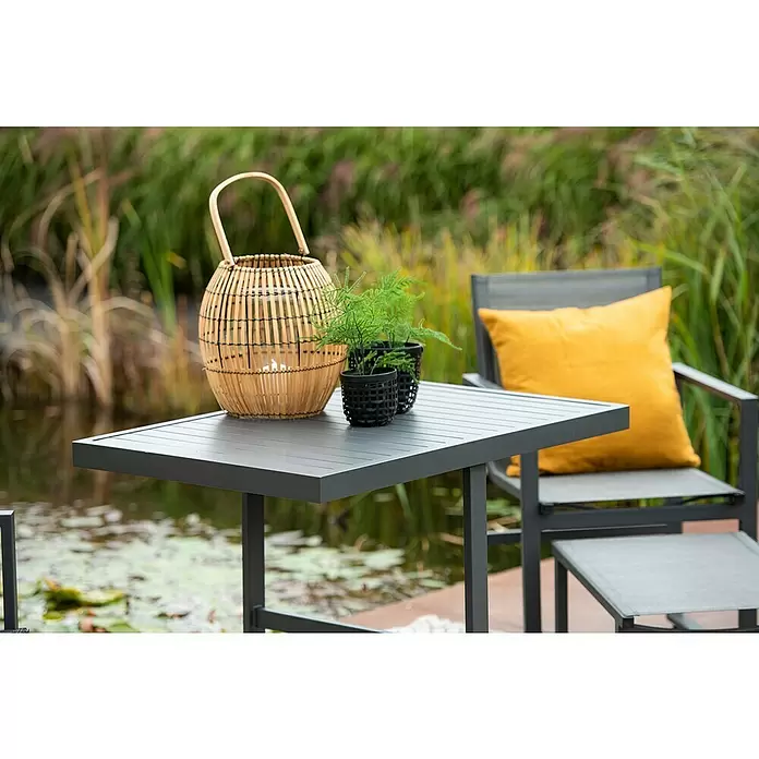 Garden Impressions Balkonmöbel-Set Alabama - 5 -tlg., Aluminium, Textilene, Schwarz/Anthrazit - Dunkelgrauer Gartentisch und Stühle mit gelbem Kissen, Bambuslaterne und Pflanzen am Teich.