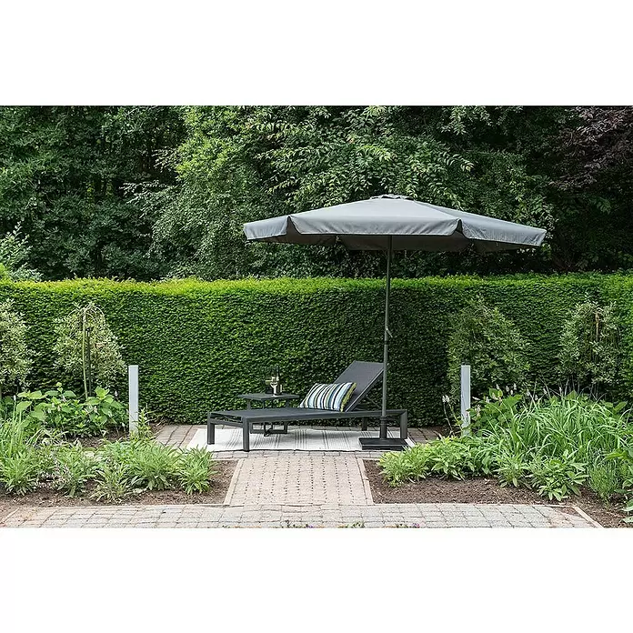 Garden Impressions Marktschirm rund Delta - Dunkelgrau, Durchmesser Bespannung: 300 cm - Graue Sonnenliege mit Beistelltisch, gestreiftem Kissen und Sonnenschirm auf einer Gartenterrasse.