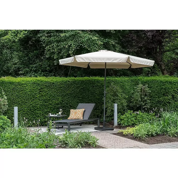 Garden Impressions Marktschirm rund Delta - Ecru, Durchmesser Bespannung: 300 cm - Beiger Sonnenschirm spendet Schatten über einer dunkelgrauen Liege und einem Beistelltisch im Garten.