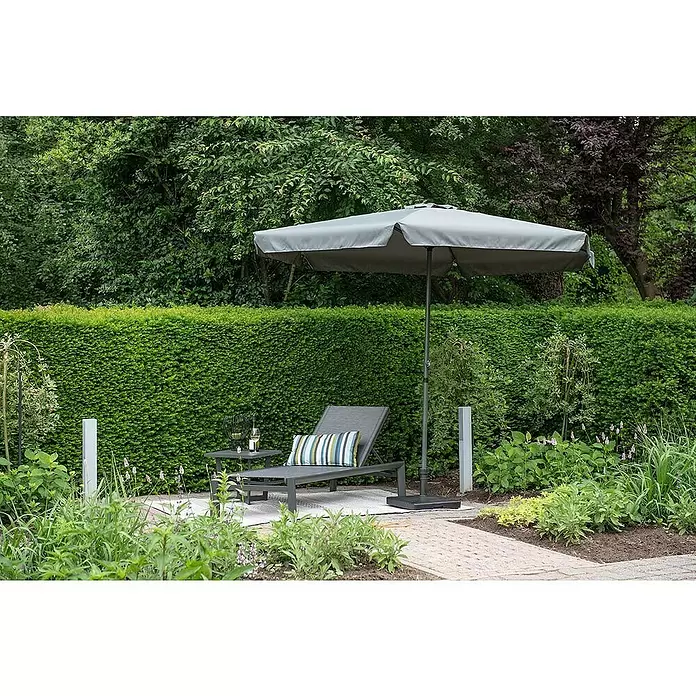 Garden Impressions Marktschirm rund Delta - Dunkelgrau, Durchmesser Bespannung: 300 cm - Dunkelgraue Gartenliege mit gestreiftem Kissen, passendem Beistelltisch und hellgrauem Sonnenschirm auf einer Gartenterrasse.