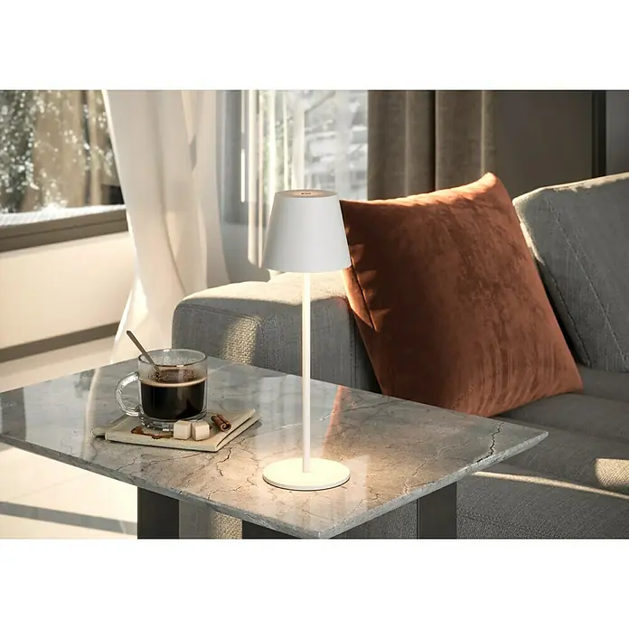 Starlux Paola Akku-Tischleuchte - 3 W, L x B x H: 11 x 11 x 36 cm, Weiß, Warmweiß - Nahaufnahme einer eleganten, weißen Tischleuchte neben einer Tasse Kaffee auf einem Marmortisch, die eine gemütliche Atmosphäre schafft.