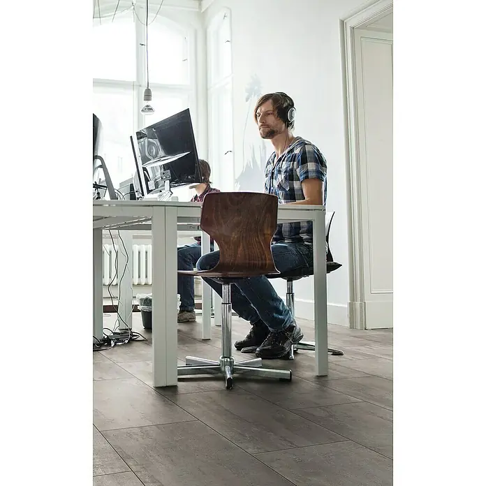 Krono Original Laminat Organic Classic - Crosstown Traffic, Fliese, 638 x 330 x 8 mm - Der Bürostuhl ist aus braunem Holz mit einem silbernen Metallfuß. Ideal für das Büro, ergonomisch und stilvoll.