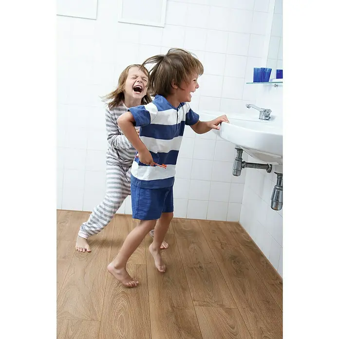 Krono Original Laminatmuster Organic Classic Historic Oak - 297 x 195 x 8 mm, Landhausdiele - Fröhliche Kinder toben im Badezimmer mit einer Zahnbürste. Sie scheinen Spaß zu haben beim Zähneputzen.