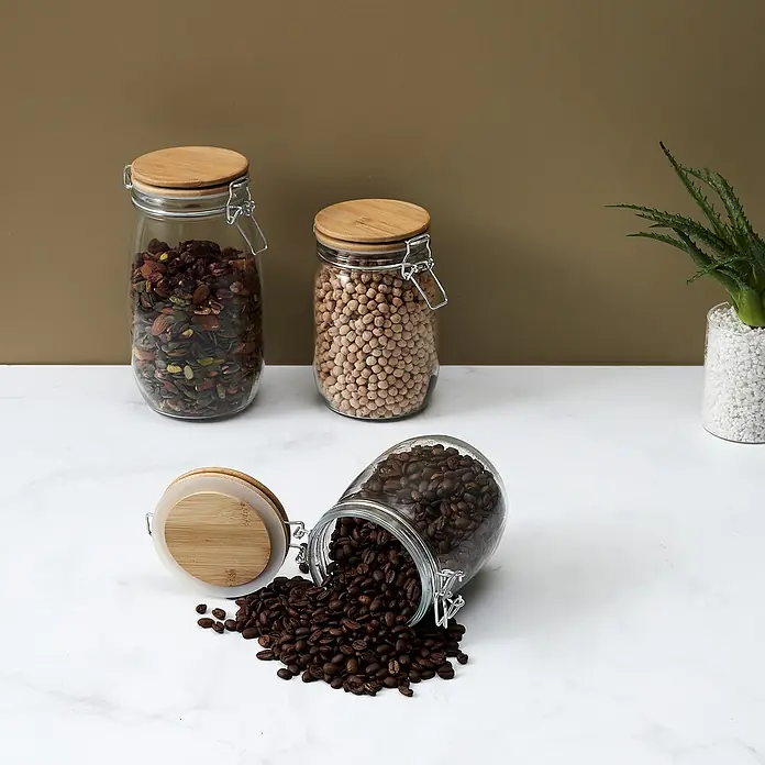Frasco con cierre mecánico Bambú - 1,5 l, Vidrio, 1 pzs. - Tres tarros con tapas de bambú herméticas llenas de semillas, garbanzos y granos de café decoran la mesa de la cocina.