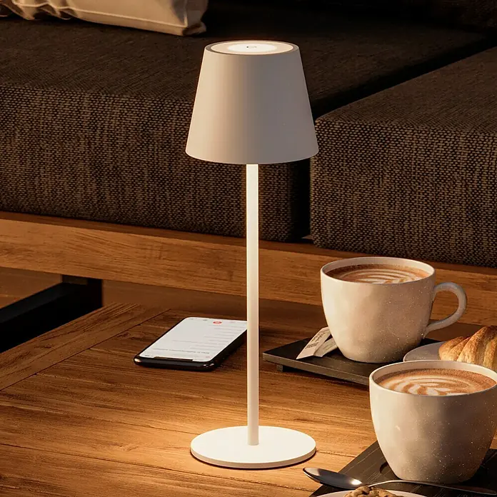 Starlux Paola Akku-Tischleuchte - 3 W, L x B x H: 11 x 11 x 36 cm, Weiß, Warmweiß - Elegante Tischleuchte neben zwei Tassen Kaffee und einem Smartphone.