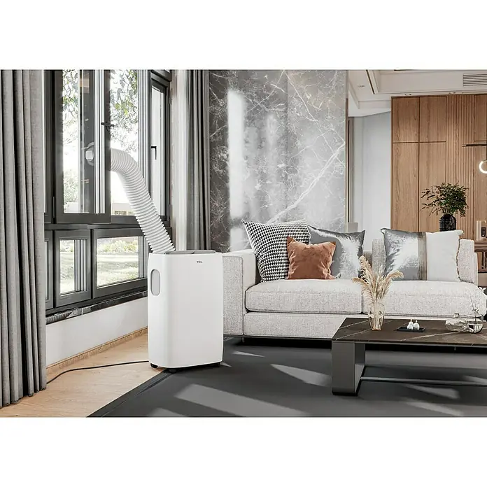 TCL Mobiles Klimagerät TAC-12CPA/KA - 3,2 kW, Raumgröße: 35 m², Weiß - Das Bild zeigt eine TCL tragbare Klimaanlage in einem modernen Wohnzimmer mit einem Fensteranschluss.