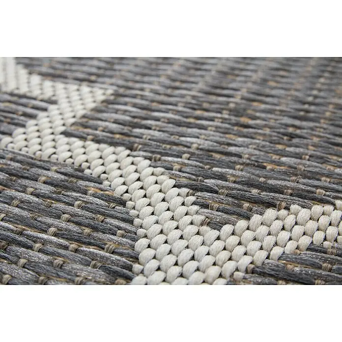 Outdoor-Teppich Sunset - Grau, 170 x 120 cm, 100 % Polypropylen - Nahaufnahme eines grau-weißen Teppichs mit einem geometrischen Webmuster, das die Textur und das Design des Teppichs hervorhebt.