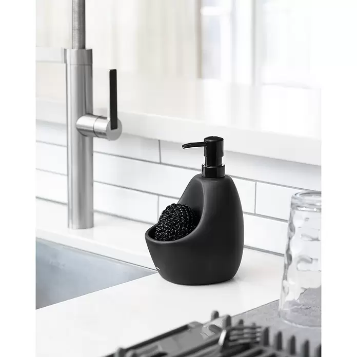 Umbra Seifenspender Joey - Kunststoff, Schwarz, 590 ml - Schwarzer Seifenspender mit integriertem Scheuerbürstenhalter an einem Küchenwaschbecken.