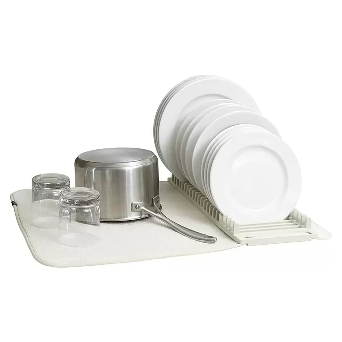 Umbra Abtropfmatte Udry - L x B x H: 61 x 46 x 4 mm, Kunststoff, Beige - Eine weiße Abtropfmatte mit einem Edelstahltopf, zwei Gläsern und einem Geschirrständer mit weißen Tellern.